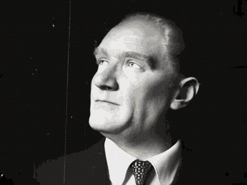 A Man In A Suit And Tie Looks Up At The Sky GIF
