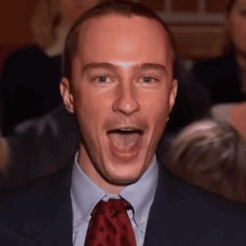 A Man In A Suit And Tie Making A Funny Face GIF