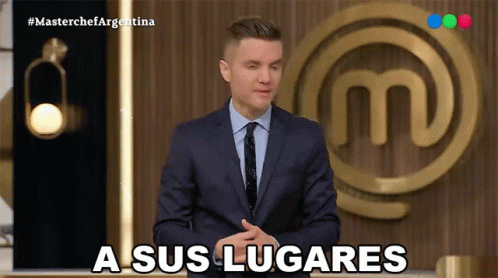 A Man In A Suit And Tie Says A Sus Lugares In Front Of A Masterchef Logo GIF