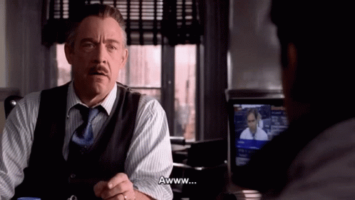 A Man In A Suit And Tie Says Awww In Front Of Another Man GIF