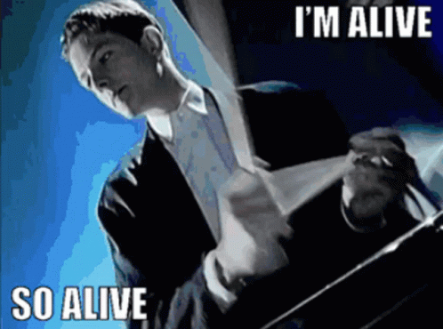 A Man In A Suit And Tie Says I 'M Alive GIF