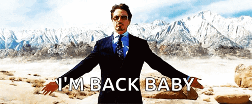 A Man In A Suit And Tie Says I 'M Back Baby With His Arms Outstretched GIF