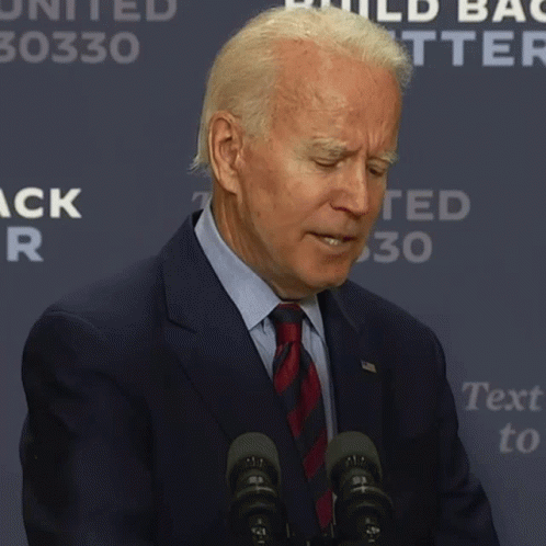A Man In A Suit And Tie Says It 'S Hard While Standing In Front Of Microphones GIF
