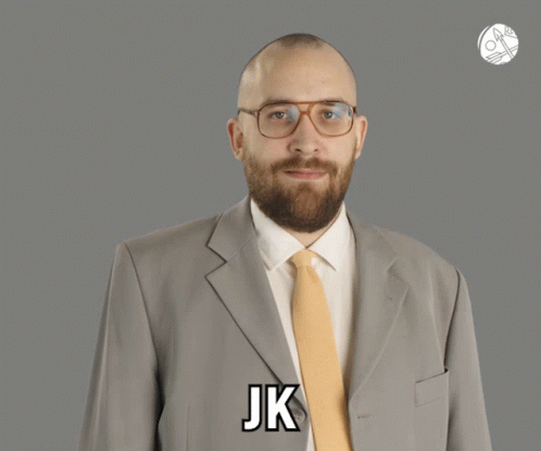 A Man In A Suit And Tie Says Jk On His Chest GIF