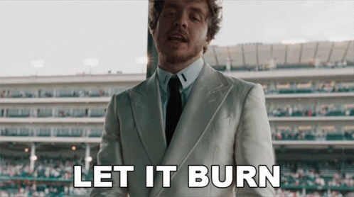 A Man In A Suit And Tie Says Let It Burn In Front Of A Stadium GIF