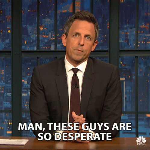A Man In A Suit And Tie Says " Man These Guys Are So Desperate " While Sitting At A Desk GIF