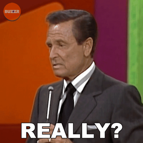 A Man In A Suit And Tie Says " Really " In Front Of A Microphone GIF