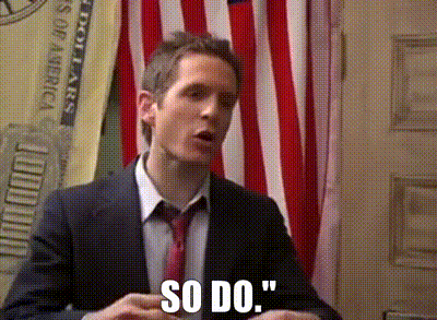 A Man In A Suit And Tie Says So Do In Front Of An American Flag GIF