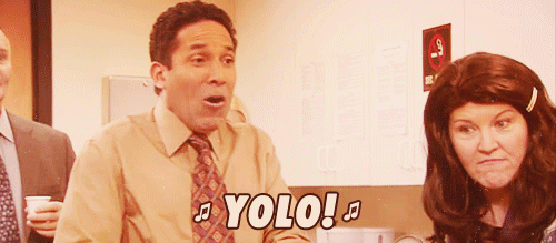 A Man In A Suit And Tie Says " Yolo " In Front Of A Woman In A Wig GIF