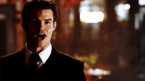 A Man In A Suit And Tie Screams With His Mouth Open GIF