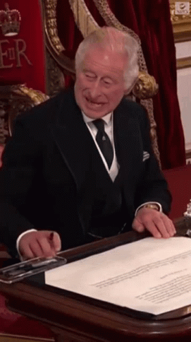 A Man In A Suit And Tie Signing A Document GIF