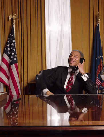 Man In Suit And Tie Talking On Phone At Desk GIF
