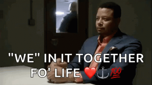 A Man In A Suit And Tie Sits At A Table With The Words " We " In It Together Fo ' Life GIF