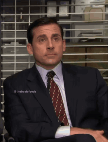 A Man In A Suit And Tie Sits In Front Of A Window GIF