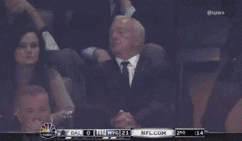 A Man In A Suit And Tie Sits In The Stands Watching A Game Between Dallas And Nyg GIF