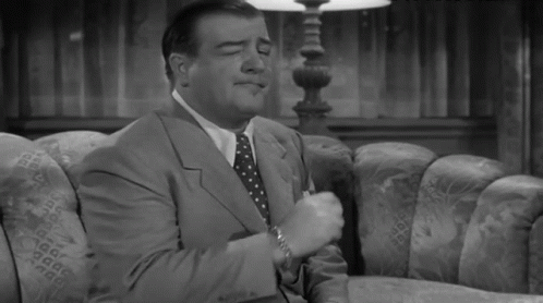 A Man In A Suit And Tie Sitting On A Couch GIF