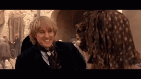 A Man In A Suit And Tie Smiles At A Woman In A Dress GIF