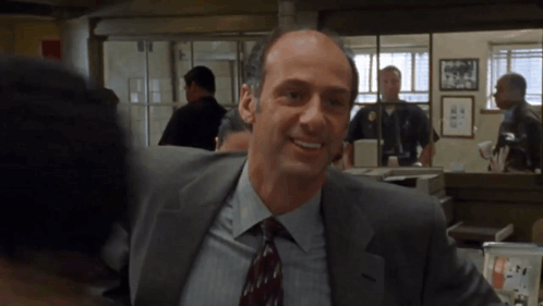 A Man In A Suit And Tie Smiles In A Room GIF