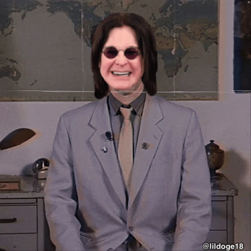 A Man In A Suit And Tie Smiles In Front Of A World Map GIF