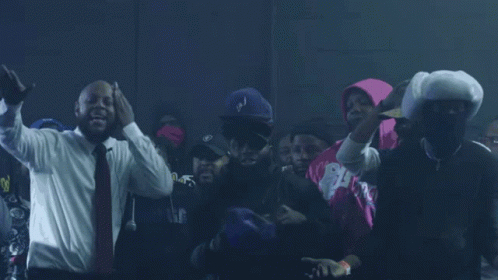 A Man In A Suit And Tie Stands In A Crowd GIF