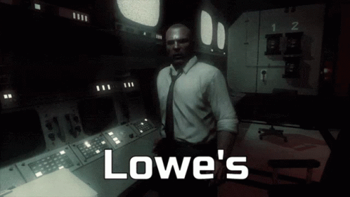 A Man In A Suit And Tie Stands In A Dark Room With The Words Lowe 'S Written On The Bottom GIF