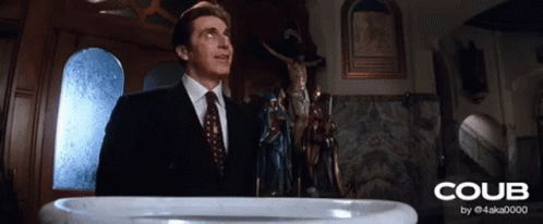 A Man In A Suit And Tie Stands In Front Of A Baptismal Font That Says Coub On It GIF