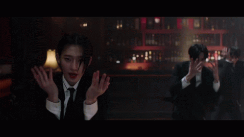 A Man In A Suit And Tie Stands In Front Of A Bar GIF
