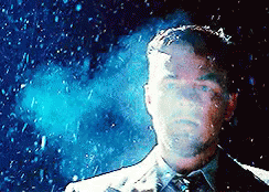 A Man In A Suit And Tie Stands In Front Of A Blue Background GIF