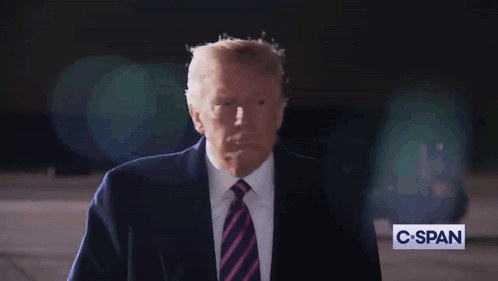 A Man In A Suit And Tie Stands In Front Of A C-Span Sign GIF