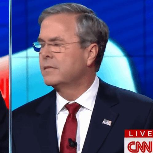 A Man In A Suit And Tie Stands In Front Of A Cnn Live Screen GIF