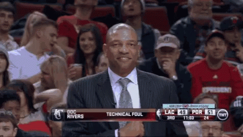 A Man In A Suit And Tie Stands In Front Of A Crowd At A Basketball Game With Technical Foul Written On The Screen GIF
