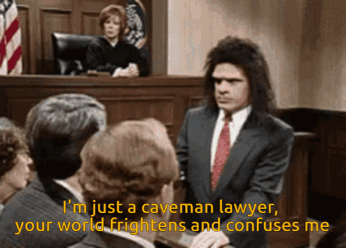 A Man In A Suit And Tie Stands In Front Of A Group Of People And Says I 'M Just A Caveman GIF