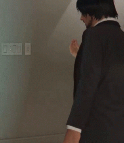 a man in a suit and tie stands in front of a light switch