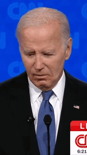 A Man In A Suit And Tie Stands In Front Of A Microphone And A Cnn Logo GIF
