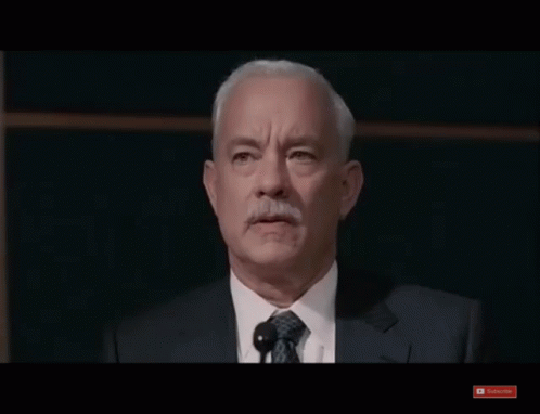 A Man In A Suit And Tie Stands In Front Of A Microphone And A Youtube Subscribe Button GIF