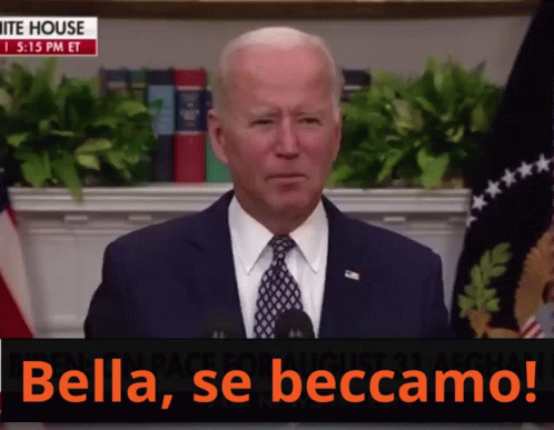 A Man In A Suit And Tie Stands In Front Of A Microphone With The Words Bella Se Beccamo On The Bottom GIF