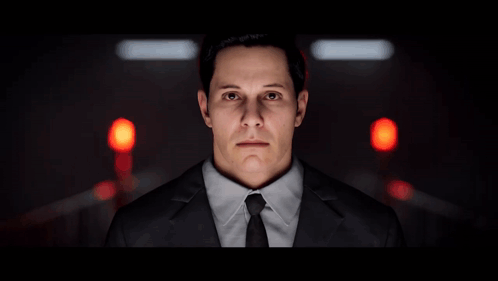 A Man In A Suit And Tie Stands In Front Of A Red Light GIF