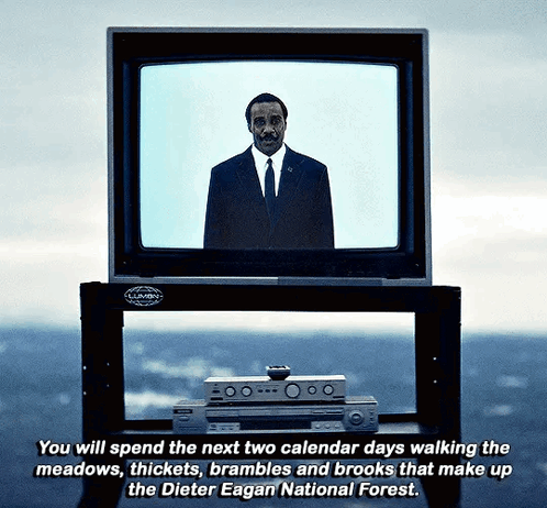 a man in a suit and tie stands in front of a television which says you will spend the next two calendar days