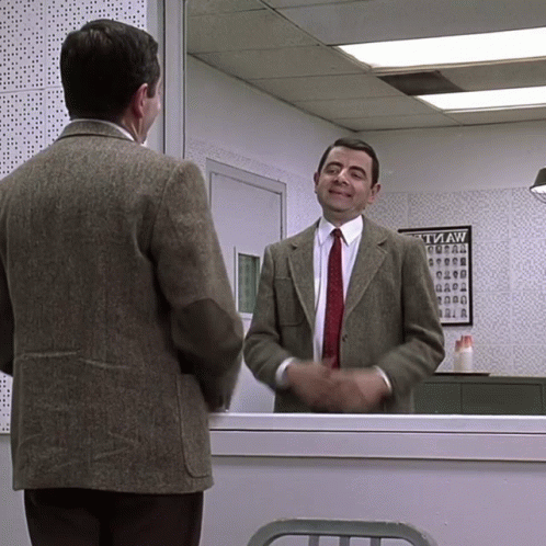 A Man In A Suit And Tie Stands In Front Of A Tvaw Poster GIF