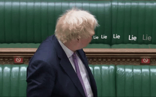 a man in a suit and tie stands in front of a wall that says lie lie lie lie lie