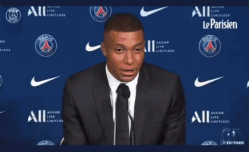 A Man In A Suit And Tie Stands In Front Of A Wall That Says Paris GIF