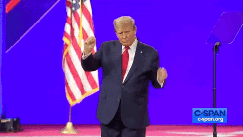 A Man In A Suit And Tie Stands In Front Of An American Flag And A Sign That Says Cspan.org GIF