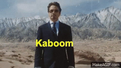 A Man In A Suit And Tie Stands In Front Of Mountains With The Word Kaboom Written On The Screen GIF
