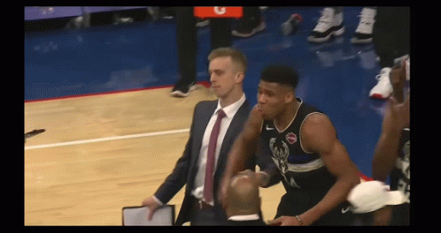 A Man In A Suit And Tie Stands Next To A Basketball Player Wearing A Jersey With The Letter A On It GIF