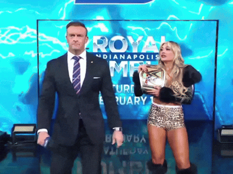 A Man In A Suit And Tie Stands Next To A Woman Holding A Trophy In Front Of A Sign That Says Royal GIF