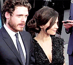 a man in a suit and tie stands next to a woman in a dress