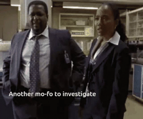 A Man In A Suit And Tie Stands Next To A Woman In A Lab With The Words Another Mo-Fo To Investigate GIF