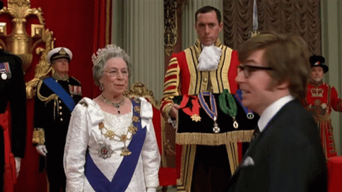 A Man In A Suit And Tie Stands Next To A Woman In A White Dress GIF