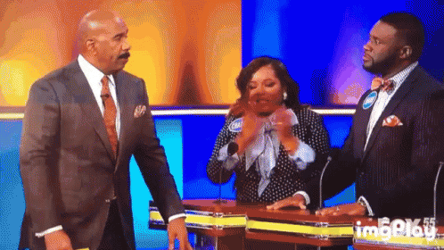 A Man In A Suit And Tie Stands Next To A Woman On A Stage GIF