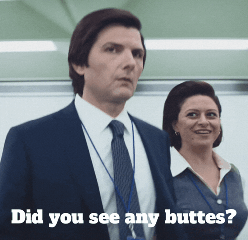 A Man In A Suit And Tie Stands Next To A Woman With The Words " Did You See Any Butts " Written Below Him GIF